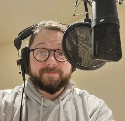 Keith Higinbotham behind a studio microphone. He's looking into the camera.